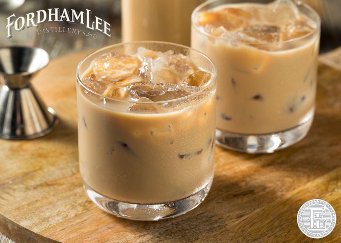 Two Glasses Of Fordham Lee Distillery’s Rich Cream Liqueur Served Over Ice, Placed On A Wooden Surface With A Jigger In The Background. The Fordham Lee Logo Is Displayed, Emphasizing The Smooth And Indulgent Nature Of The Liqueur.